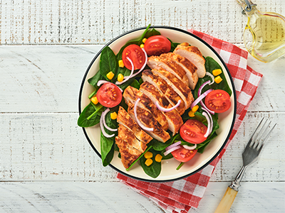 a plate of chicken with spinach and tomatoes